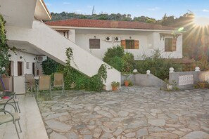 Ein Gebäude mit einem kiesschottergepflasterten Innenhof, einer Treppe und Blick auf einen Hügel.