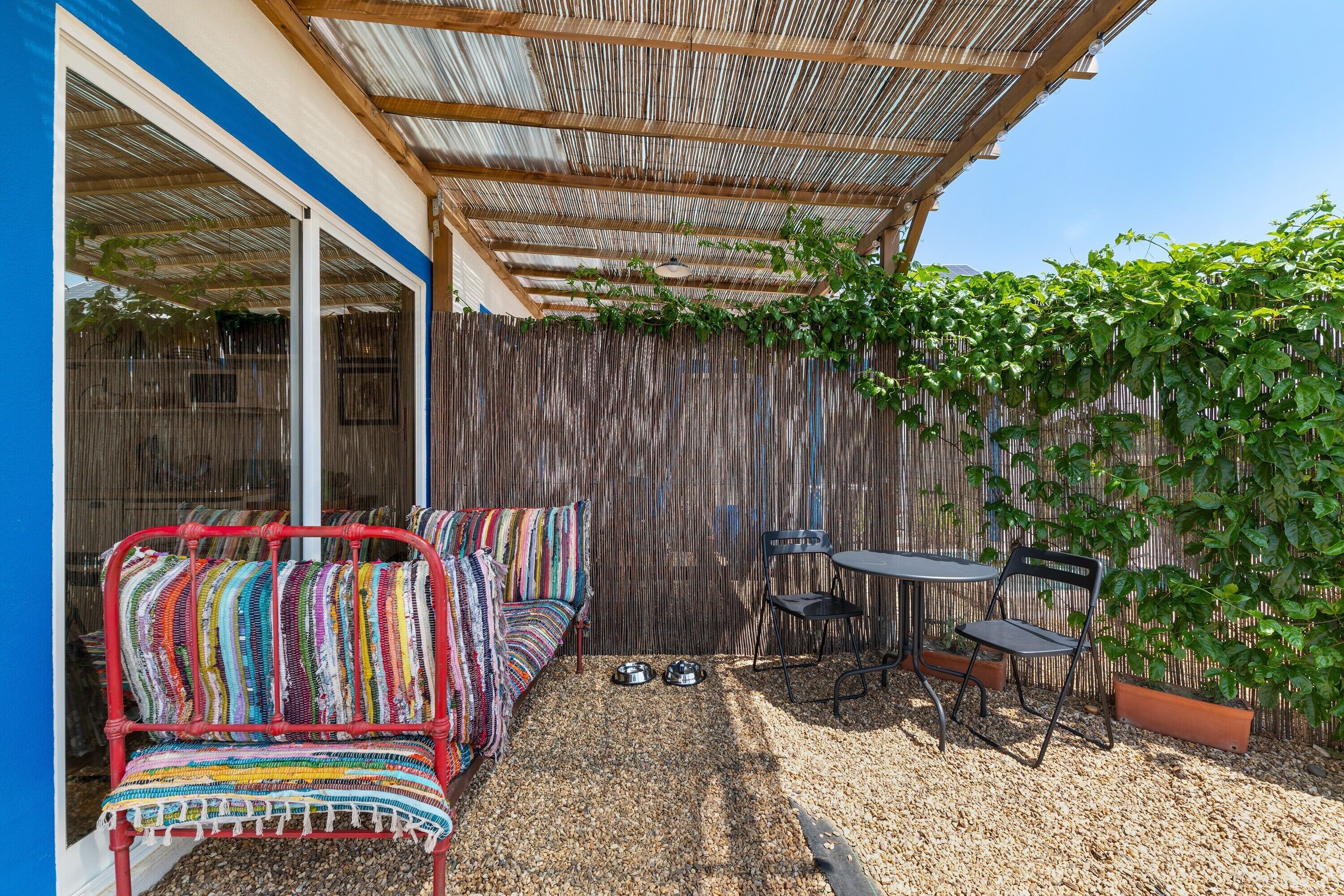 A patio area with a colorful woven sofa, a small round table, and chairs.