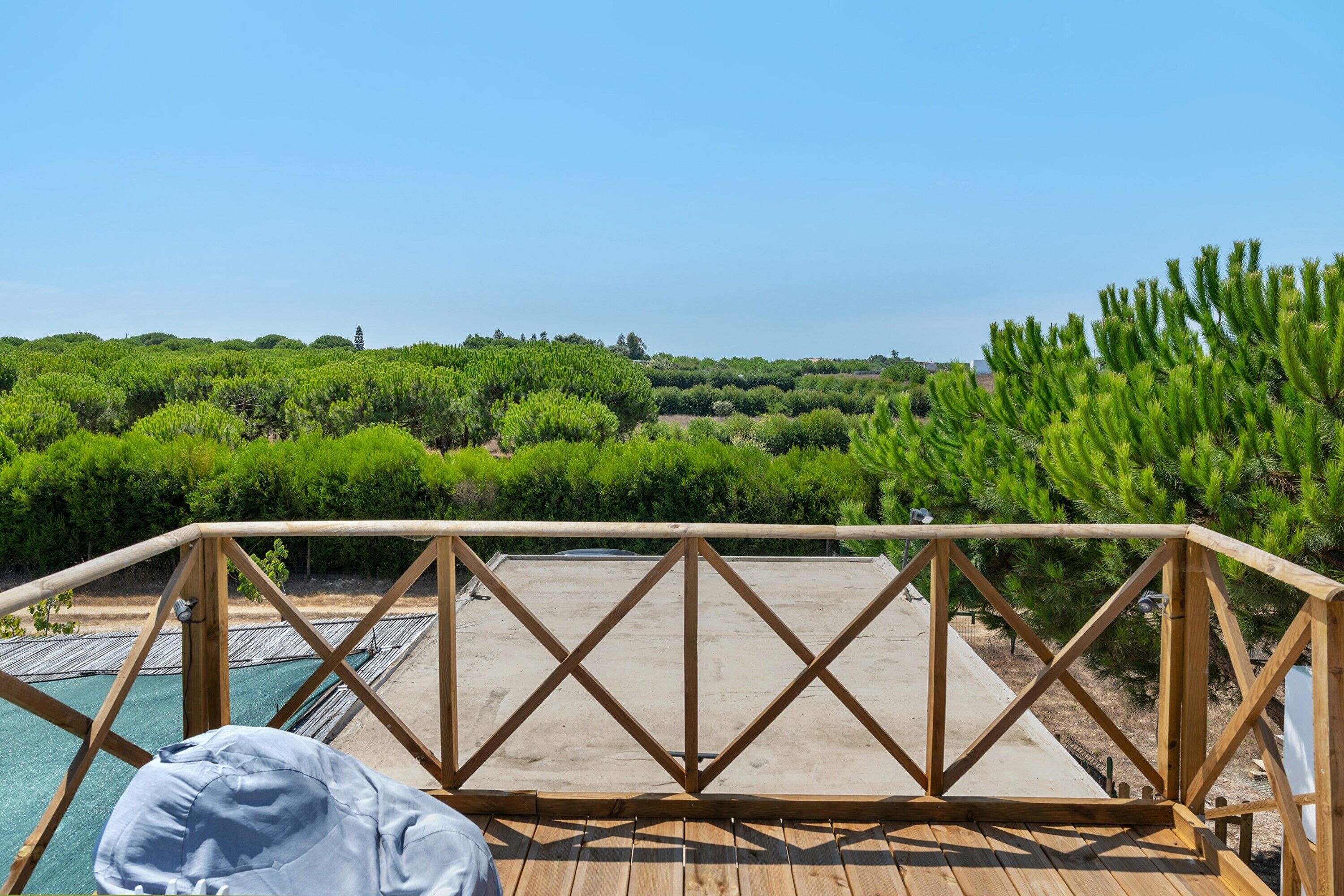 A wooden deck with a view of a landscaped area and a pool.