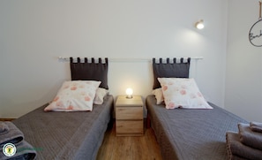 Ein Doppelzimmer mit zwei Betten, jedes mit Kissen und einem Nachttisch mit Lampe.