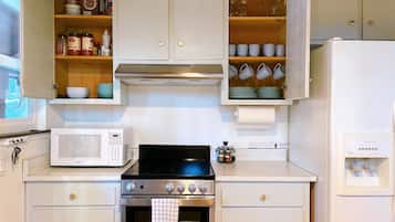 Una cocina con estufa, microondas, horno y armarios.