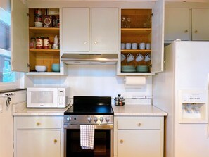 A kitchen with a stove, microwave, oven, and cabinets.