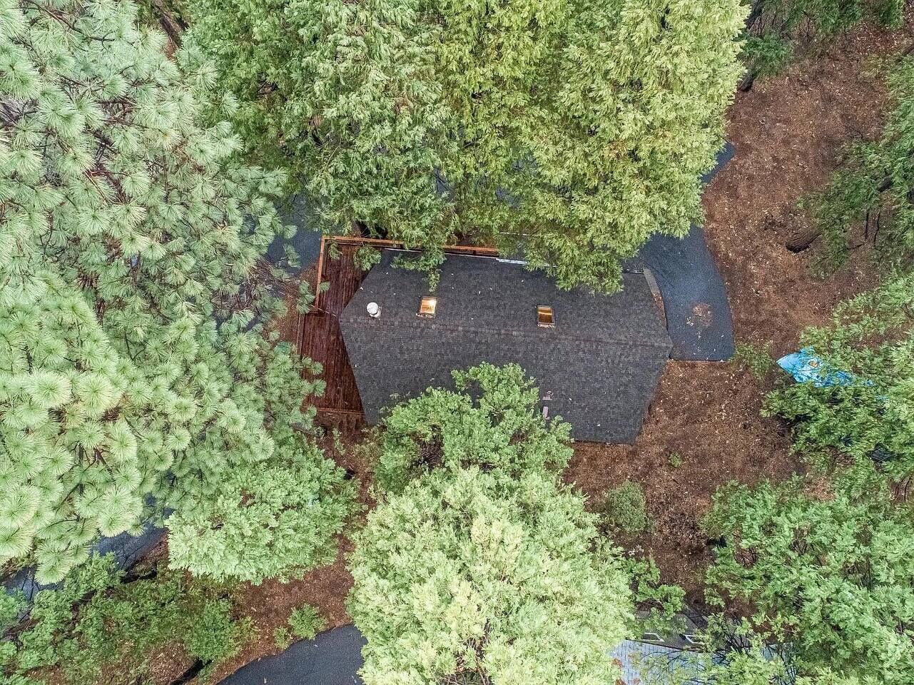 An aerial view of a property with a fenced area, a paved path, and dense greenery.