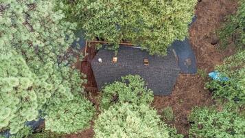An aerial view of a property with a fenced area, a paved path, and dense greenery.