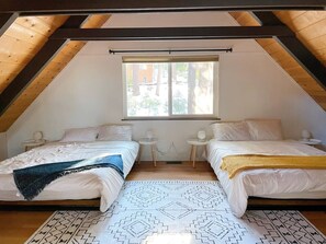 A room with two beds, a window, and a patterned rug.