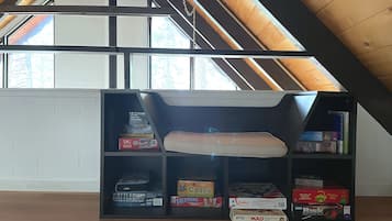 Ein Loft-Zimmer mit schrägem Dach, einer eingebauten Bücherwand und einer gepolsterten Sitzbank.