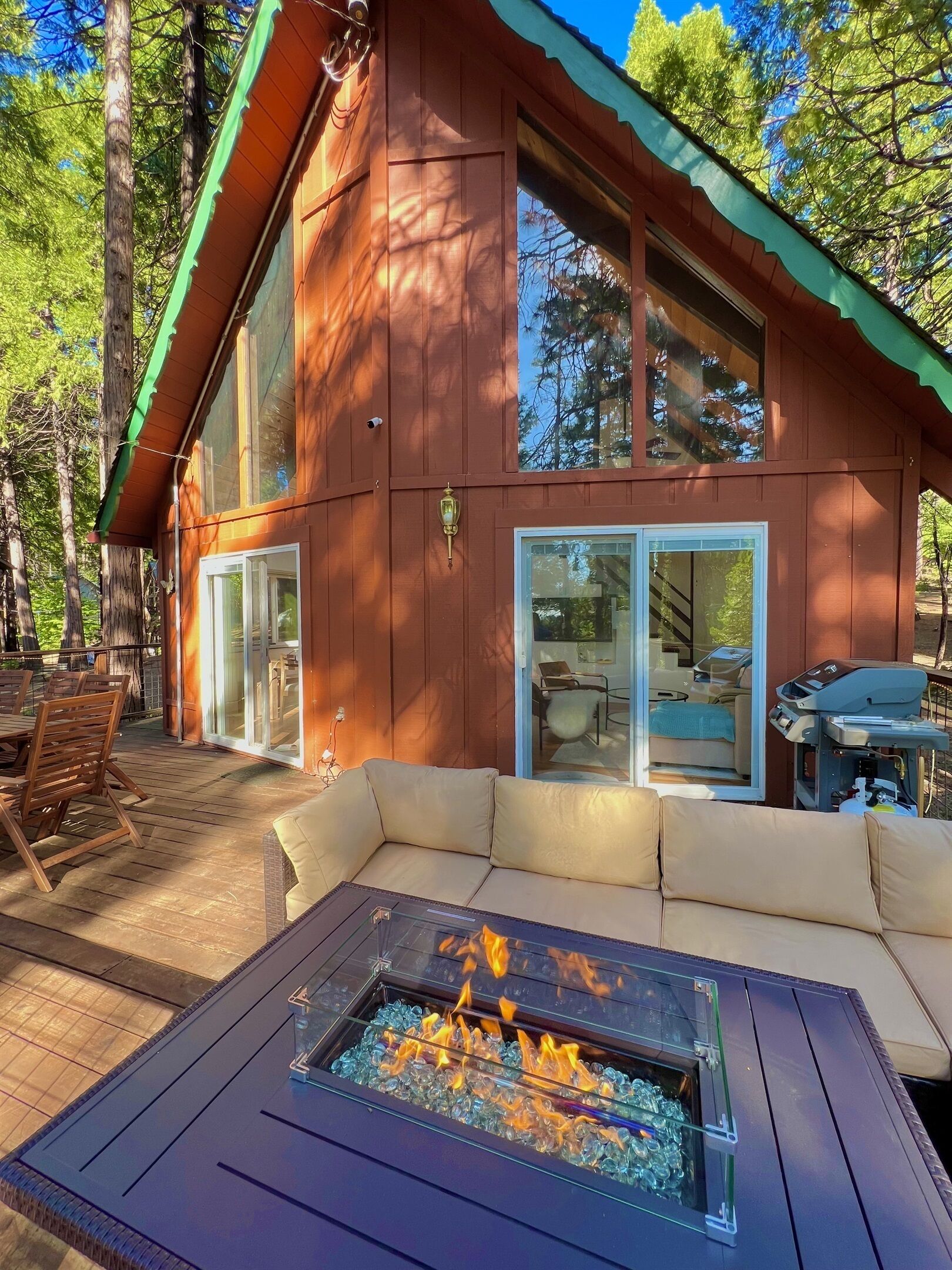A cabin with a glass-enclosed fire pit, outdoor seating, and a deck.