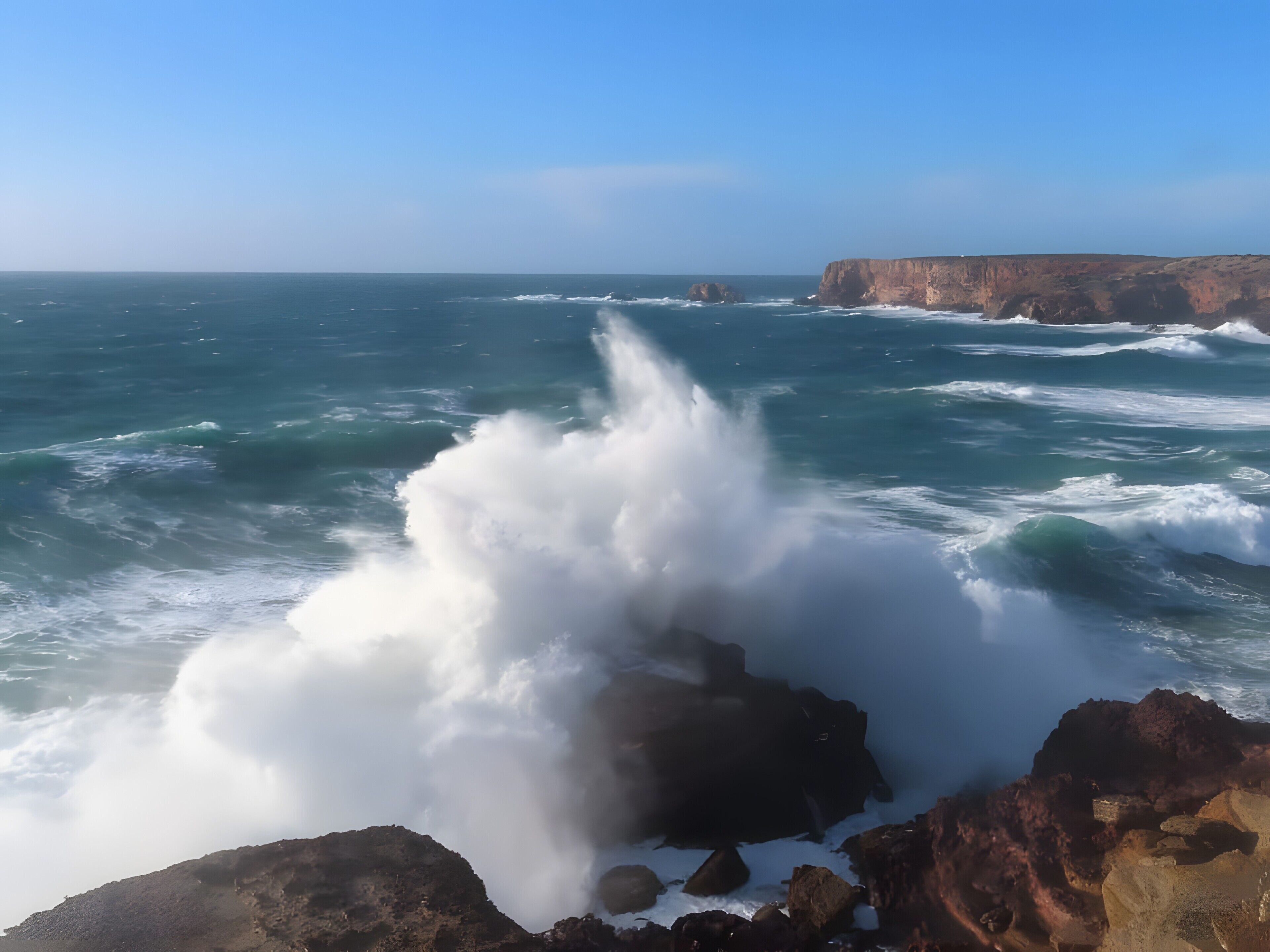 Paisaje costero con olas rompiendo contra las rocas.
