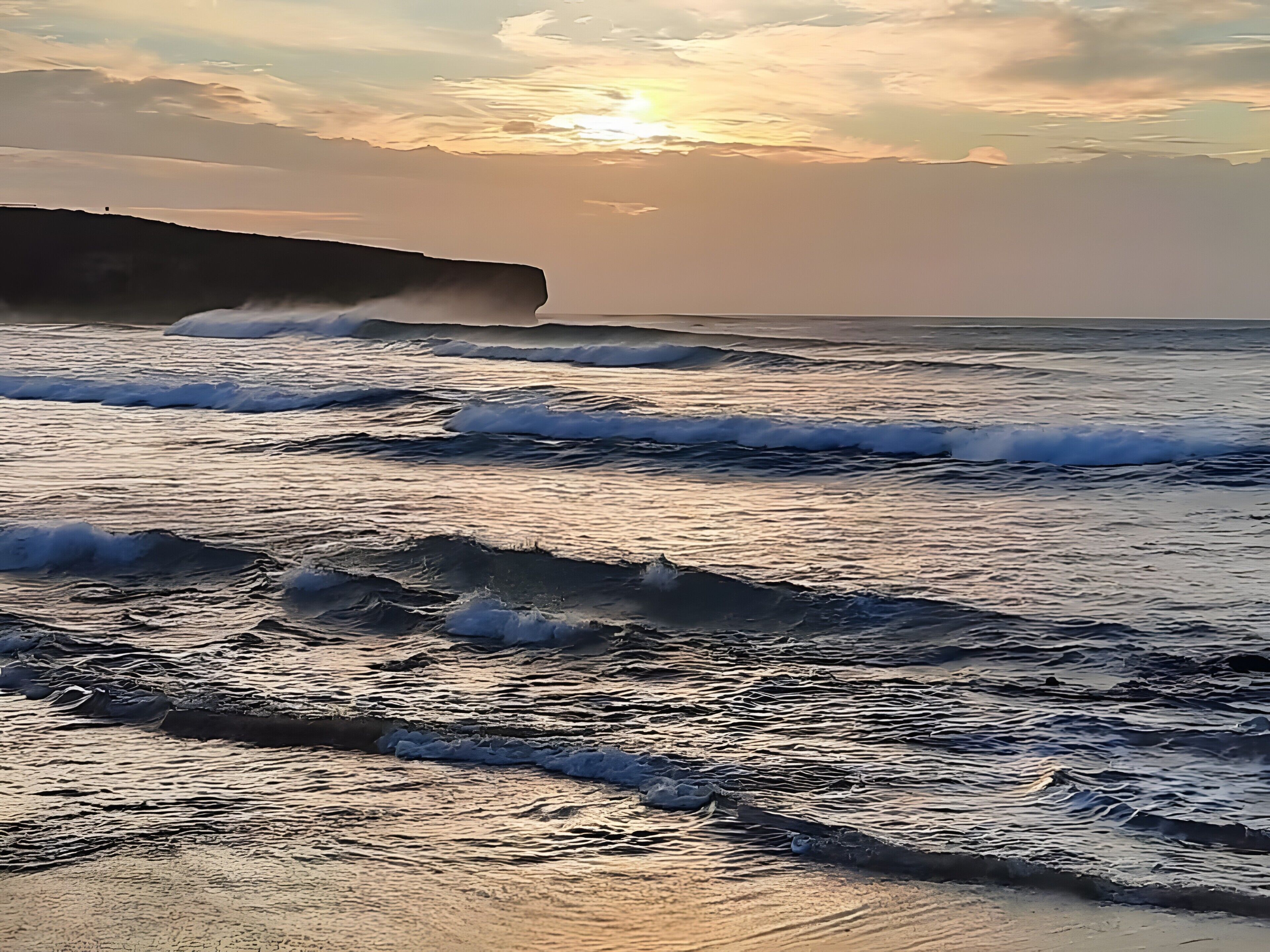 A coastal scene with waves and a cliff.