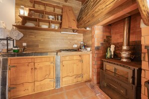 Una cocina rústica con armarios de madera, un horno de ladrillo y un estante de madera sobre la encimera.