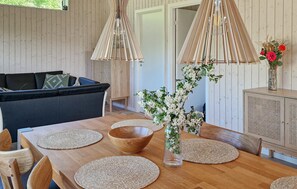Ein Holztisch mit gewebten Tischsets, eine Holzschüssel und eine Vase mit Blumen.