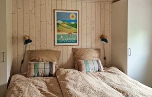 Ein Schlafzimmer mit einem Bett, zwei Kissen, einem gerahmten Bild an der Wand und zwei Wandleuchten.