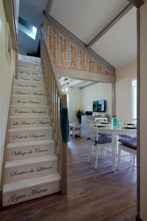 A staircase with steps labeled with names, leading to a dining area with a table and chairs. - La Dune Blanche Vacation Rental - GUJAN MESTRAS (GUJAN MESTRAS)