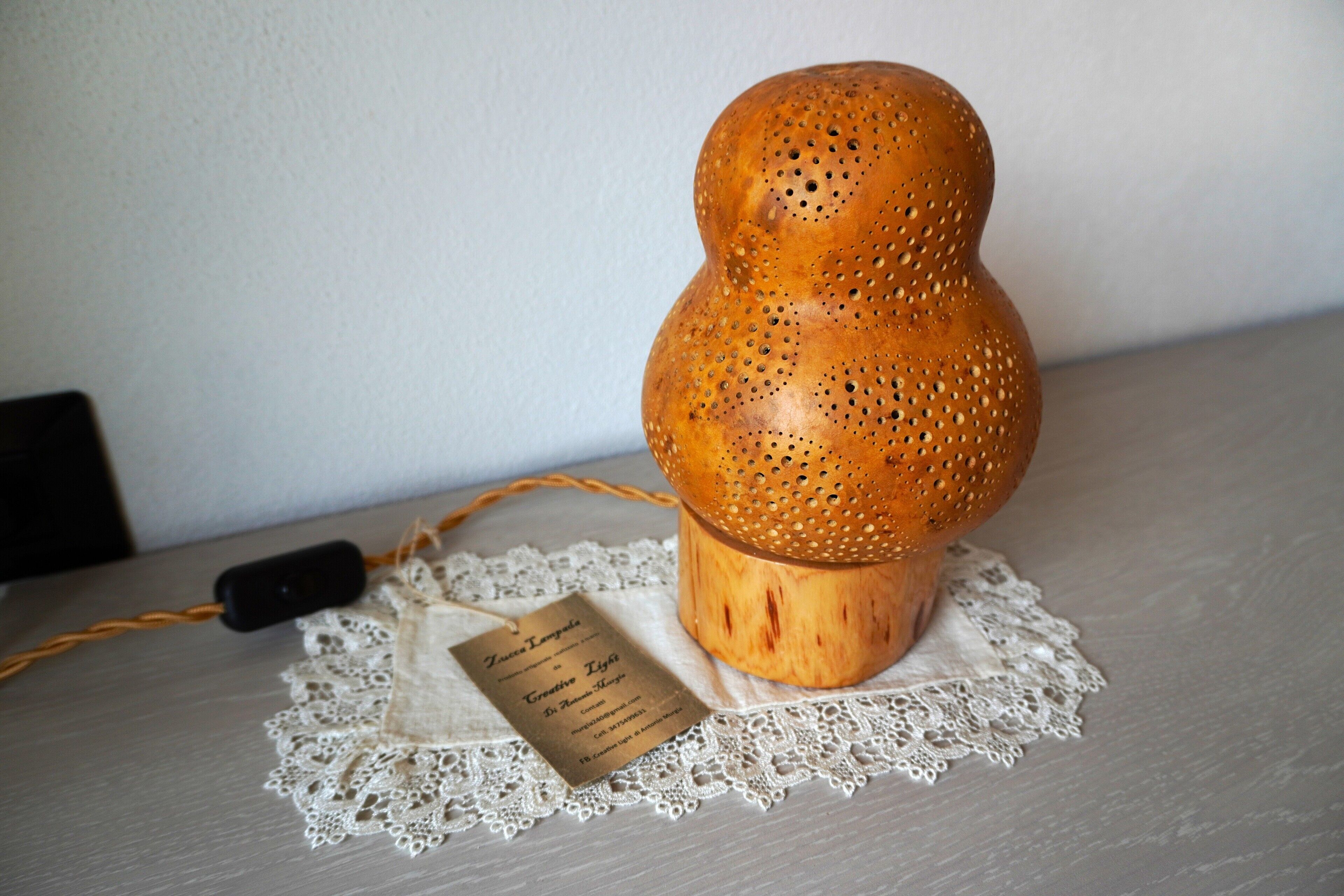 A wooden lamp with a label on a lace doily.