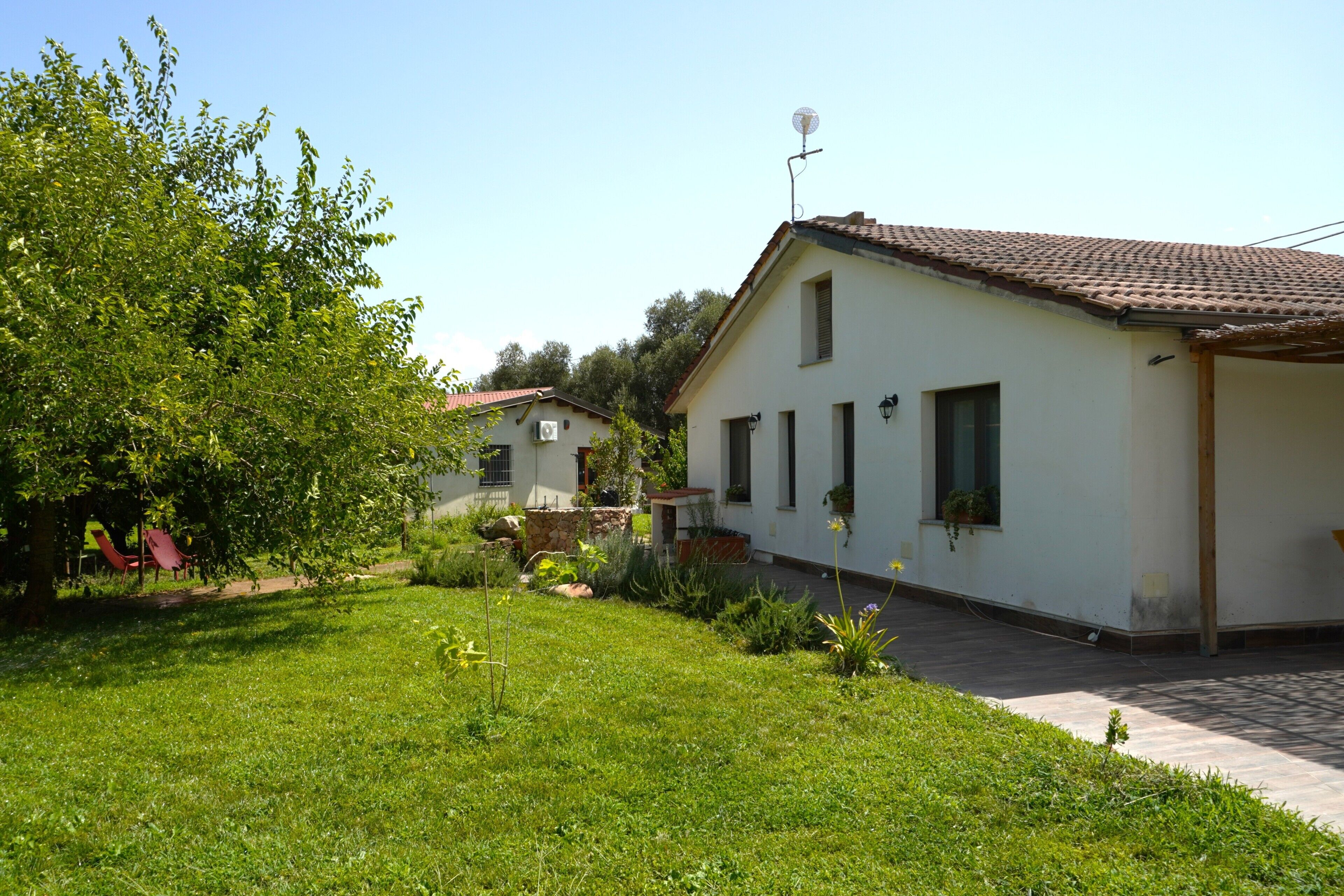 Ein Wohnhaus mit gepflegtem Rasen, einer Terrassenanlage und einem Dach mit Ziegeldeckung.