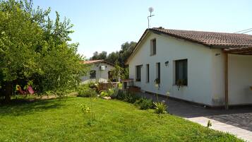 Ein Wohnhaus mit gepflegtem Rasen, einer Terrassenanlage und einem Dach mit Ziegeldeckung.
