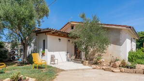 Una casa de una sola planta con un patio, mobiliario exterior y un jardín.