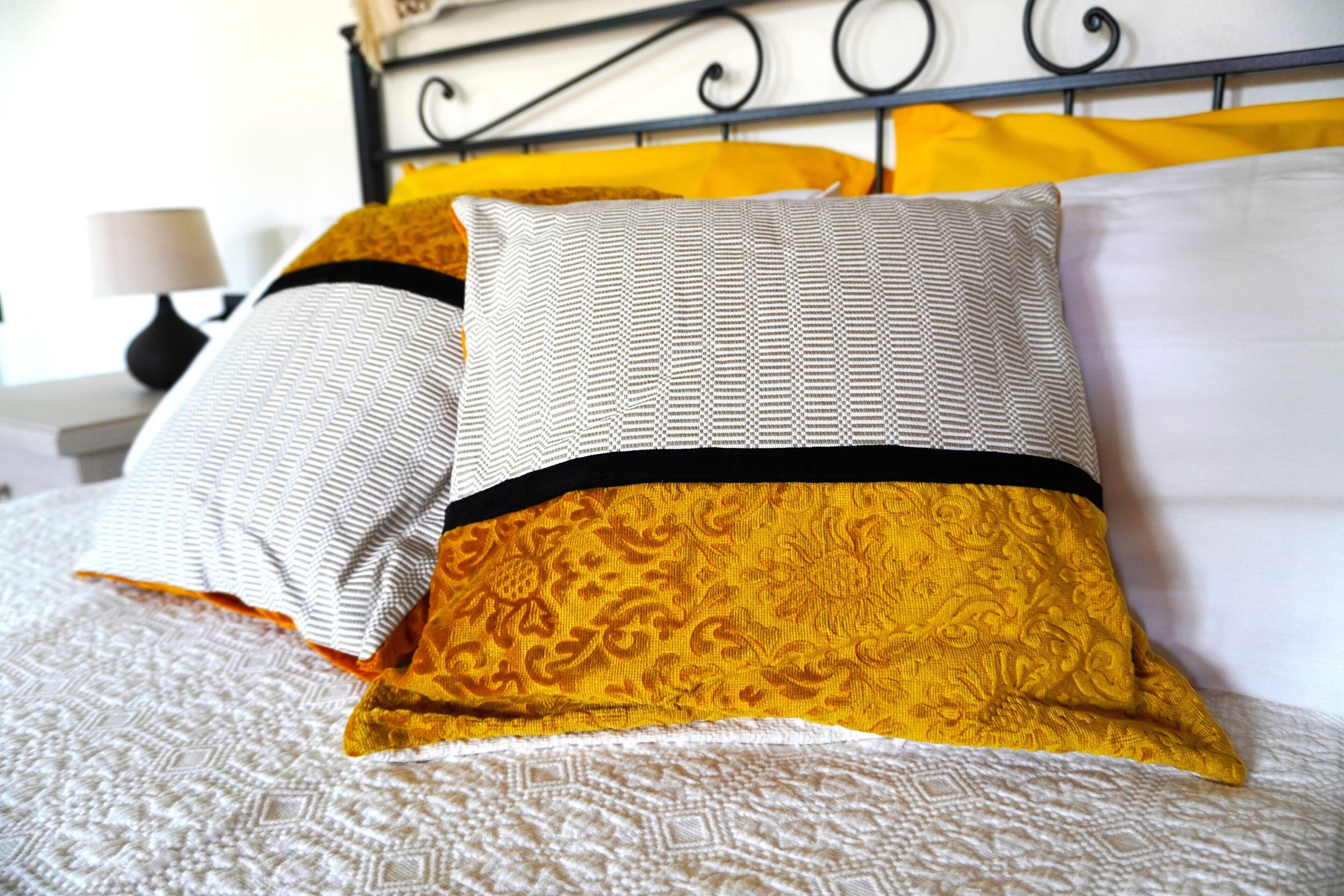 Un lit avec des coussins à motifs et une tête de lit.