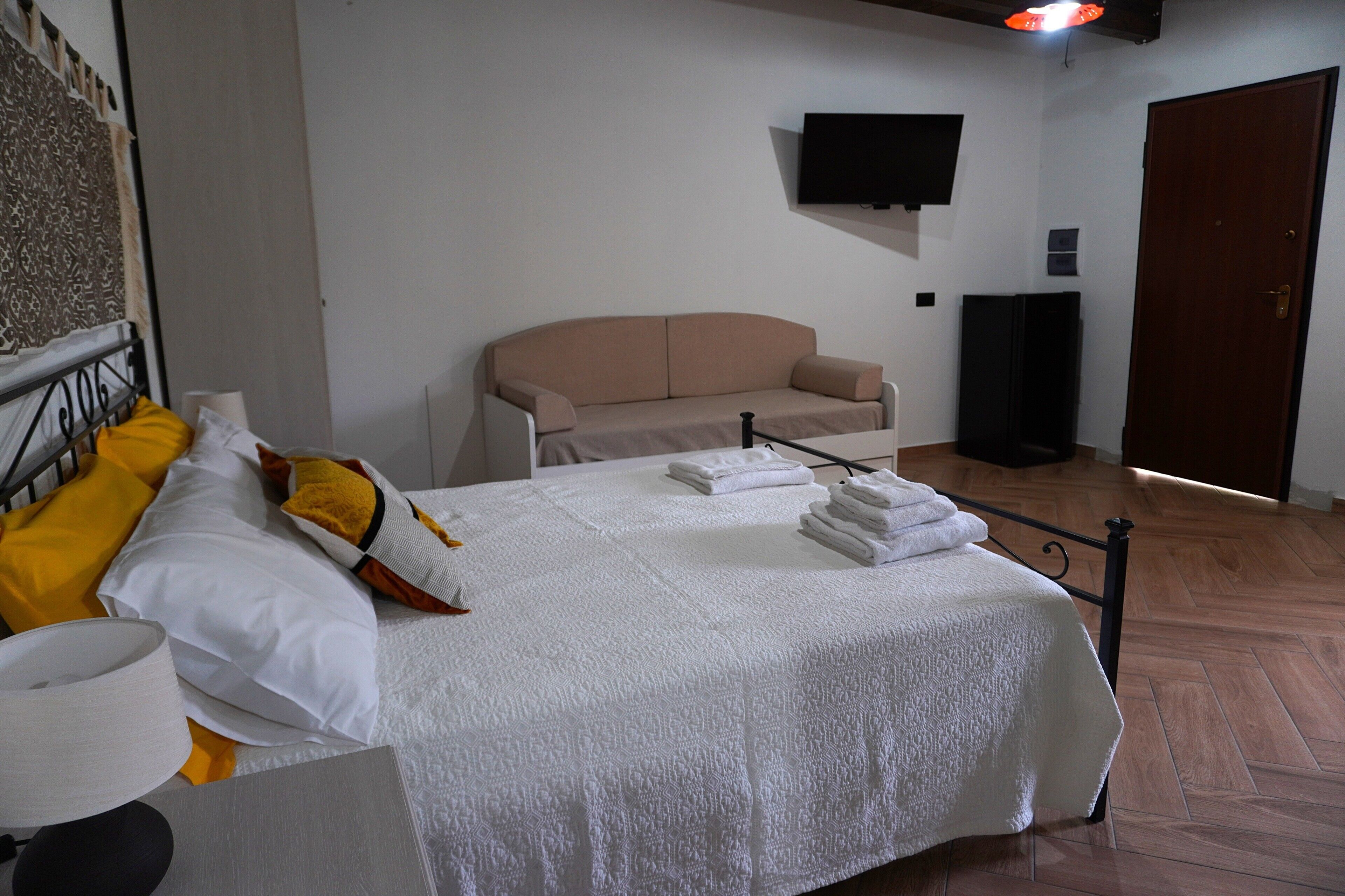 Ein Hotelzimmer mit einem Bett, einem Sofa, einem Fernseher und einer Tür.