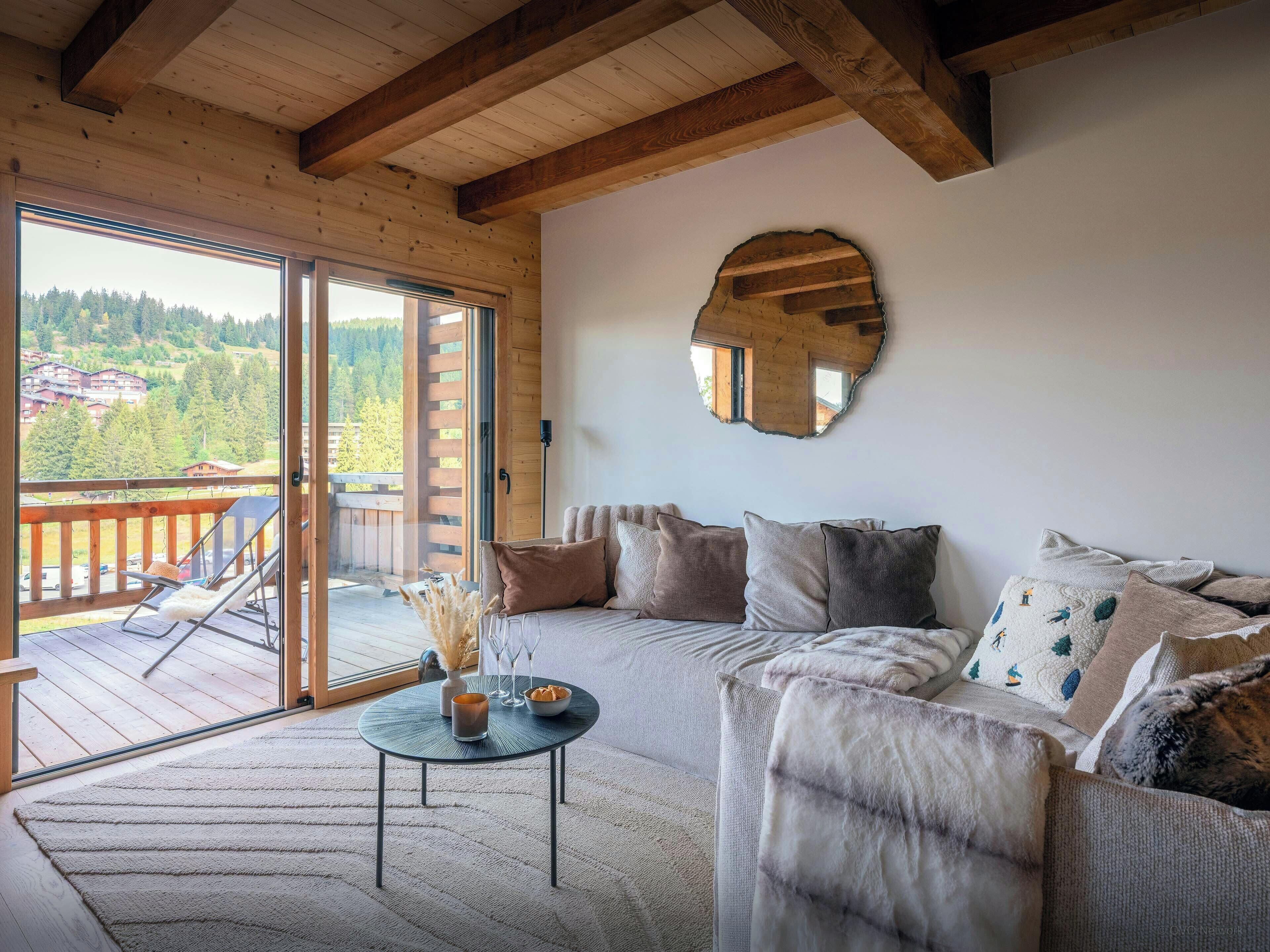 Un salon chaleureux avec un canapé, une table basse ronde et une vue sur un balcon.