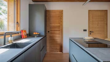 Una cocina moderna con puerta de madera, un lavamanos con dispensador de jabón y un cuenco de fruta sobre la encimera.