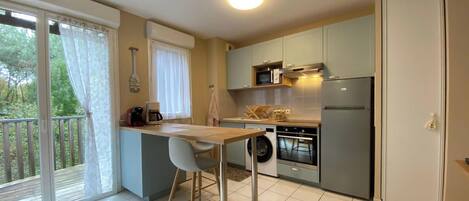 A compact kitchen with a dining area, a washing machine, and a refrigerator.
