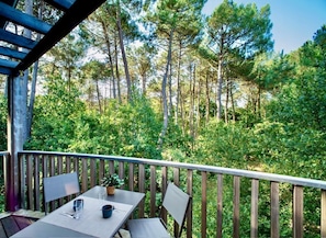 A wooden deck with a table and chairs, overlooking a forested area. - Pins & Marées - AUDENGE (AUDENGE)