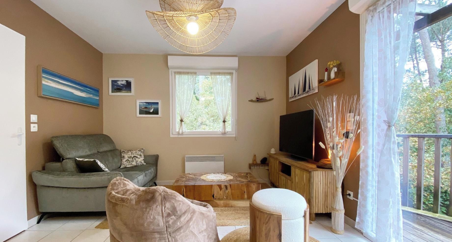 A living room with a sofa, a coffee table, a television, and a balcony with a railing.