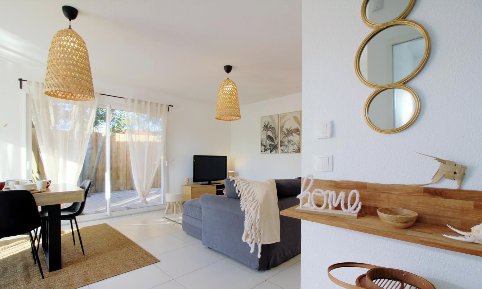 A modern living room with a sofa, a television, and a dining area with a table and chairs.