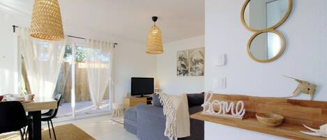 A modern living room with a sofa, a television, and a dining area with a table and chairs.