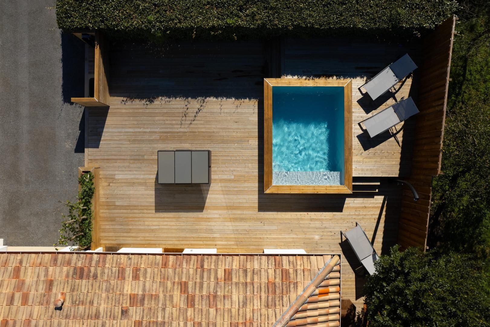 A rooftop deck with a swimming pool, seating area, and a wooden deck.
