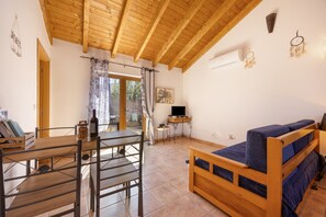 A room with a wooden ceiling, a bed with blue bedding, a table with a bottle, and a TV on a stand. - Villa 'Coureladaltura 2' with Mountain View, Wi-Fi and Air Conditioning (Aljezur)