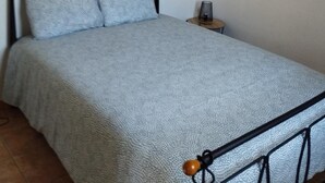 Un lit avec un cadre en métal et une couverture de lit grise à texture.