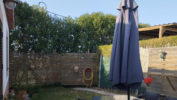 Une terrasse extérieure avec une table et des chaises, un parasol et une clôture en bois.