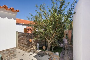A courtyard with a tiled floor, a wooden fence, and a tree. - Villa 'Coureladaltura 2' with Mountain View, Wi-Fi and Air Conditioning (Aljezur)