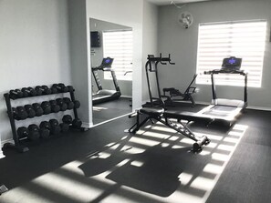 A gym with treadmills, a weight bench, and a rack of dumbbells. - The Lake Breeze Villa- 48GH (Laguna Vista)