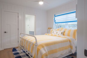 Ein Schlafzimmer mit Bett, einem Fenster mit Jalousien, einer Tür und einem Heizkörper.