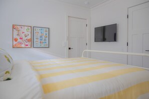 Ett sovrum med en säng, en tv som är monterad på väggen och två dörrar.