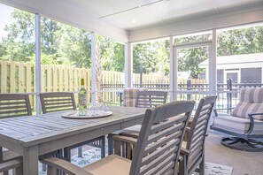 Eine Terrasss mit Esstisch, Stühlen und einer Flasche Alkohol.