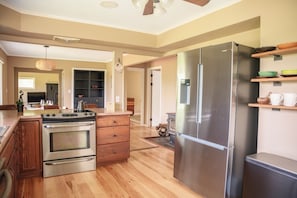 A modern kitchen with stainless steel appliances, wooden cabinetry, and a hardwood floor. - The Rutland Ranch: 3 BR/1BA Renovated Home Close to Everything (Rutland)