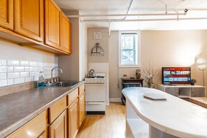 A modern kitchen with wooden cabinets, a stainless steel sink, a stove, and a dining area with a white table and chairs.