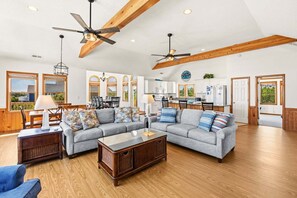 A spacious living room with a grey sofa, wooden coffee table, and a ceiling fan. - Family Affair Corolla retreat with private pool, hot tub, and easy beach access. (Corolla)