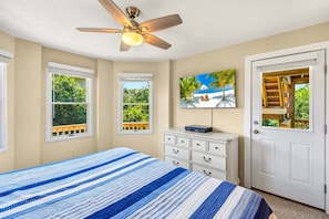 A bedroom with a bed, a ceiling fan, a dresser, and a door with a view of a balcony. - Family Affair Corolla retreat with private pool, hot tub, and easy beach access. (Corolla)