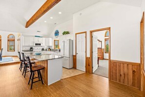 A spacious kitchen with white cabinets, a granite countertop, and a wooden ceiling beam. - Family Affair Corolla retreat with private pool, hot tub, and easy beach access. (Corolla)