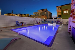 A swimming pool with a slide, surrounded by lounge chairs and a fence. - NEW 4BR/4BA Beach Retreat, Heated Pool, Slide, Elevator, Bikes, 2 Min to Ocean (Carolina Beach)