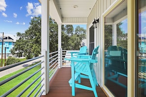 A covered outdoor area with a wooden deck, metal railing, and two chairs. - NEW 4BR/4BA Beach Retreat, Heated Pool, Slide, Elevator, Bikes, 2 Min to Ocean (Carolina Beach)