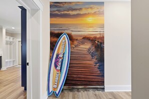 Ein Flur mit einem Wandgemälde zum Thema Strand, Holzboden und einer Tür links.