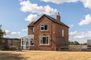 A two-story brick house with a conservatory, a fenced yard, and a wooden gate. - Leys Cottage - sleeps 2 guests (TOPCLIFFE)