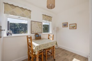 A dining area with a table, chairs, and two framed pictures on the wall. - Leys Cottage - sleeps 2 guests (TOPCLIFFE)