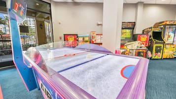 Uma pista de hóquei no gelo coberta, com uma barreira de vidro, rodeada por jogos de fliperama.